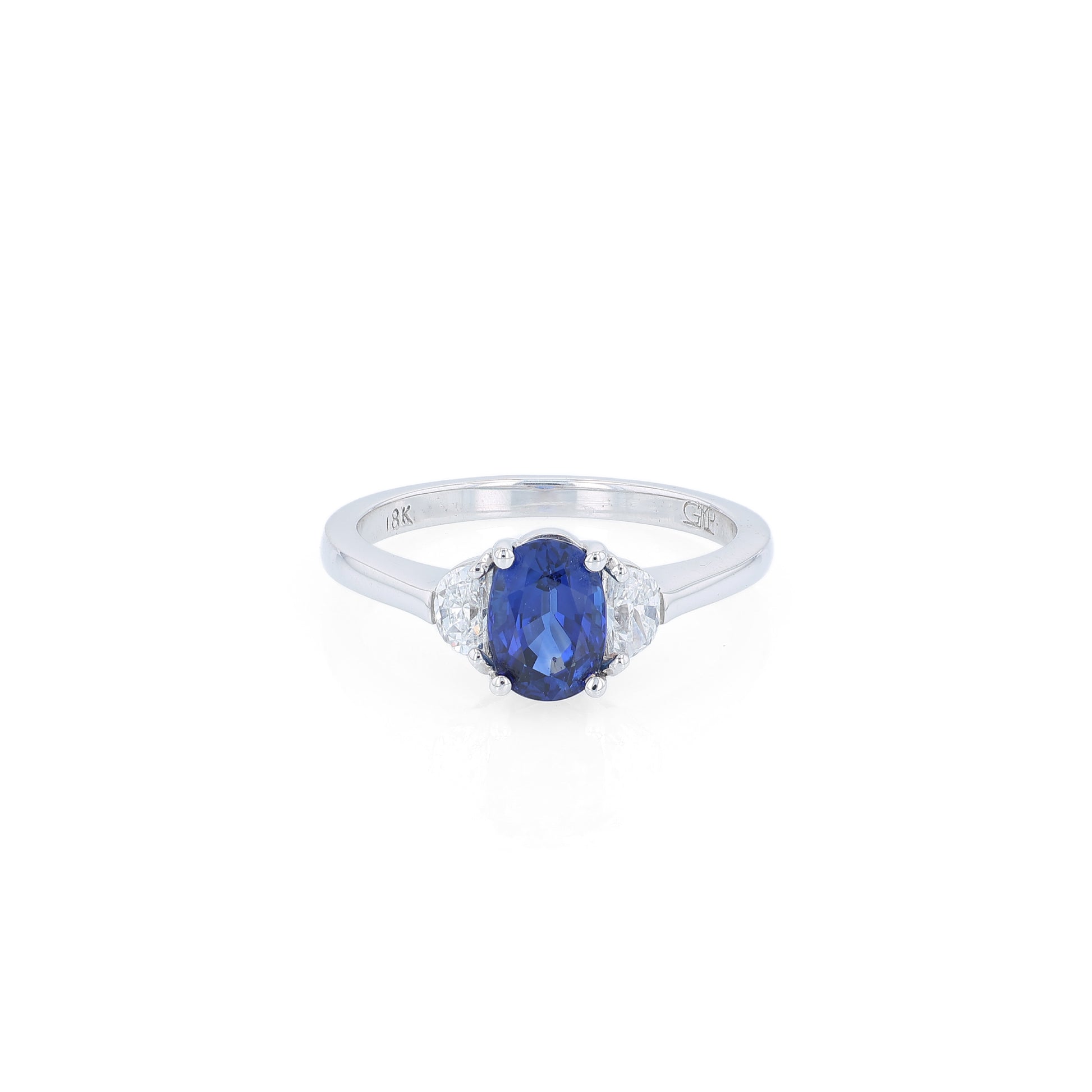 Platinum ring with an oval blue sapphire center and half moon cut diamond sides on a white background