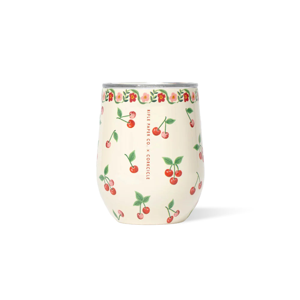 A cream stemless tumbler with red  cherries and other colorful floral designs on a white background