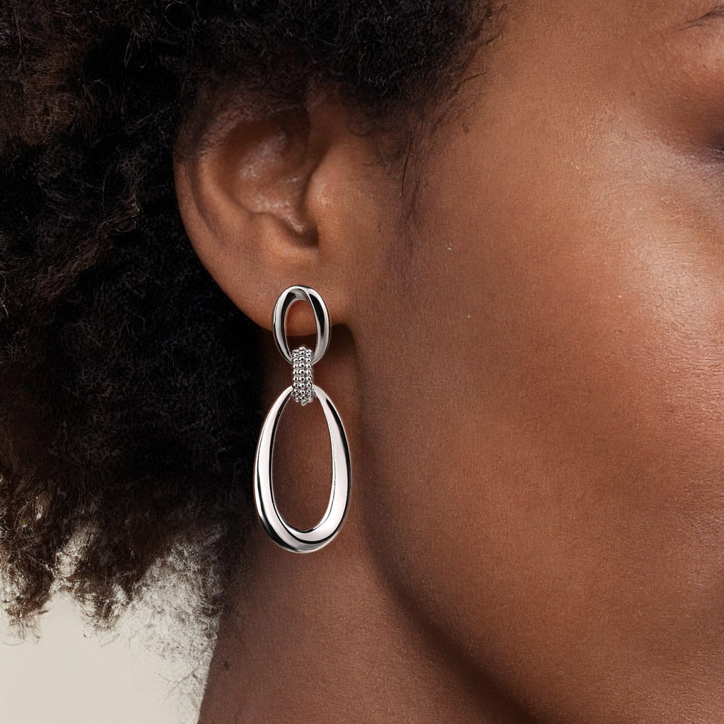 Silver hoop earring worn by a person with dark hair.