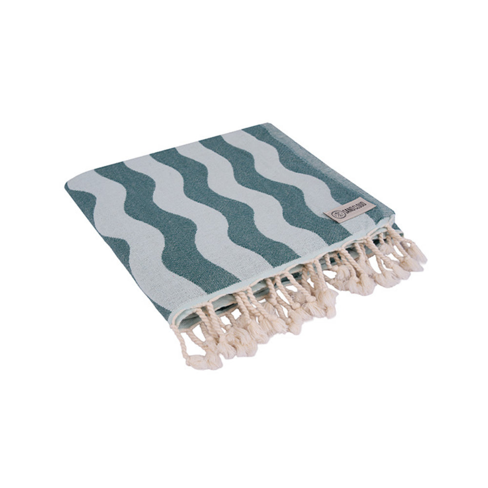 Folded teal blue beach towel with blue wavy stripes and  white tassel edge on a white background.