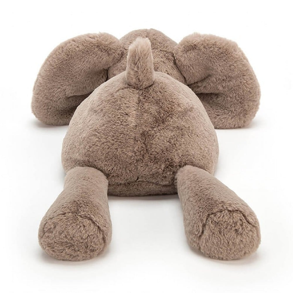 A photo of the back of a medium size plush toy elephant with soft grey-brown fur, big black eyes, and large ears on a white backround 