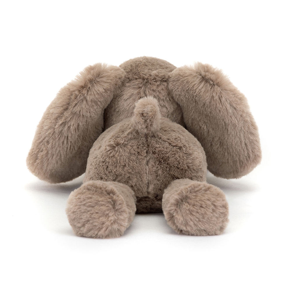 A photo of the back of a tiny sized plush toy elephant with soft grey-brown fur, big black eyes, and large ears.