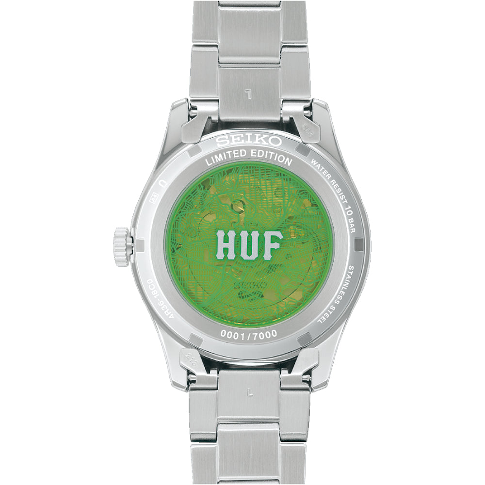 Steel Seiko watch with green "HUF" see-through case back on a white background