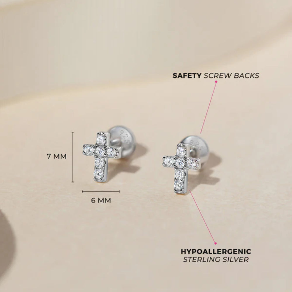 Silver cross earrings with safety screw backs on a beige background