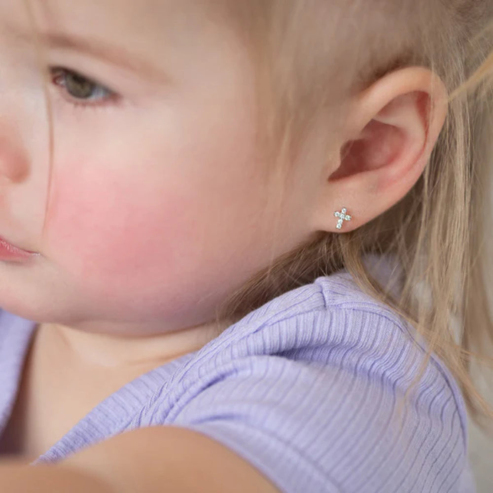 Close-up of a child wearing a small earring with a flower design.