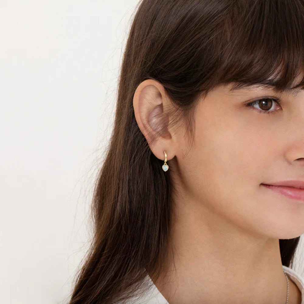 Close-up of a woman wearing a pearl earring against a plain background