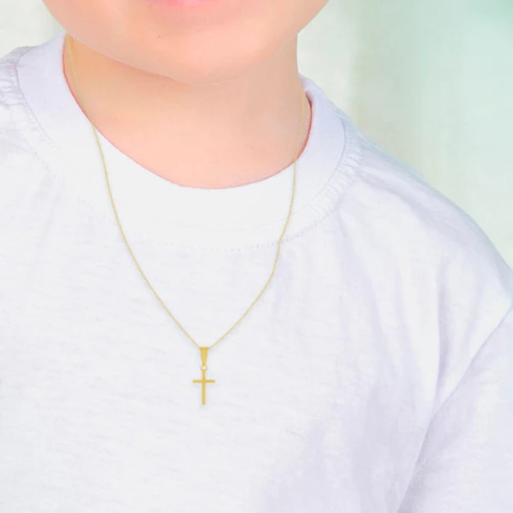 Gold cross necklace on a person wearing a white shirt with a blurred background
