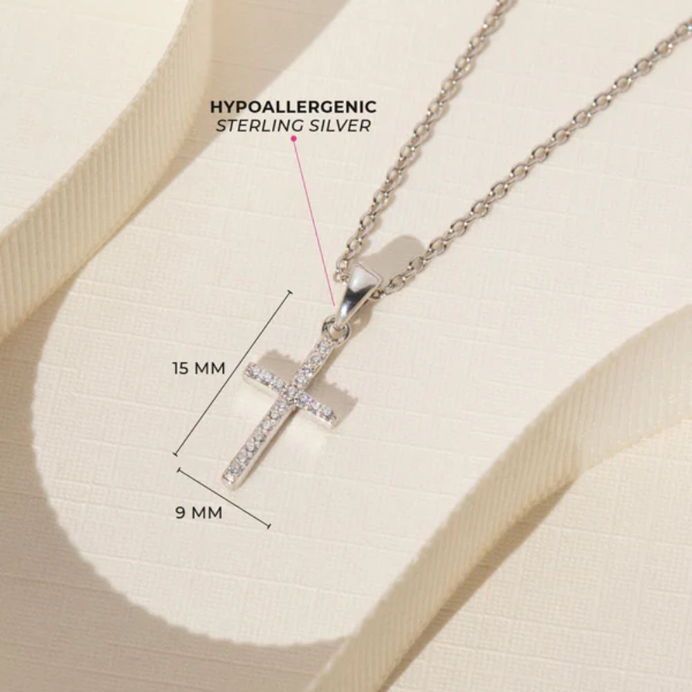Silver cross necklace with dimensions and 'hypoallergenic' label on a beige background