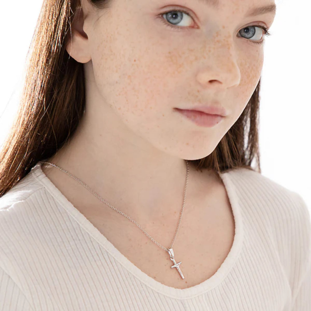 Close-up of a person wearing a silver cross necklace on a white background