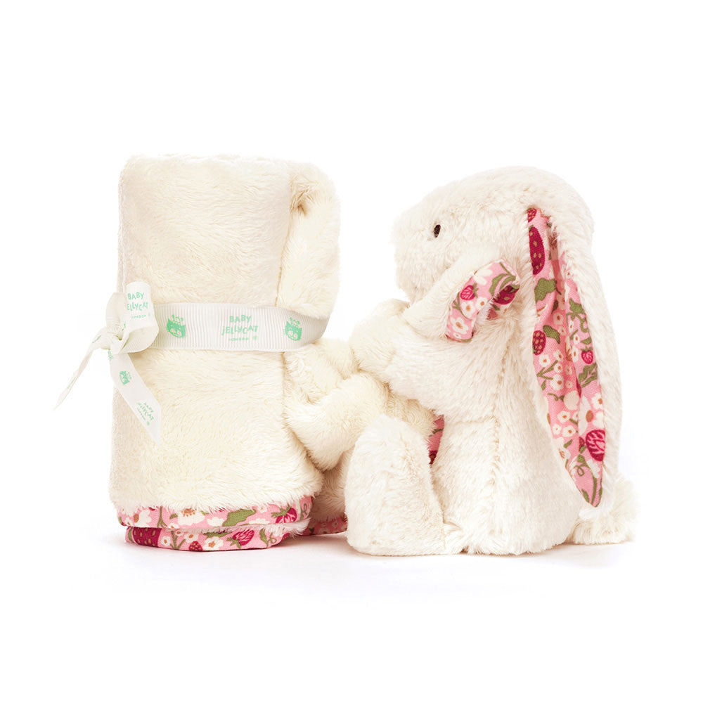 Fluffy white bunny toy with floral pattered ears blanket rolled on a white background.