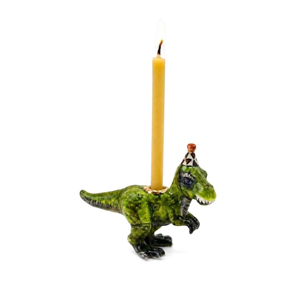 A green dinosaur-shaped candle holder with a lit yellow candle inserted into its back, set against a plain white background.