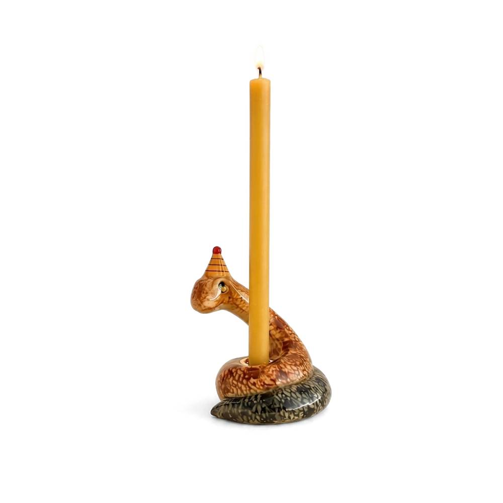 A coiled snake-shaped candle holder with a lit taper candle inserted into its head, set against a solid warm beige background.