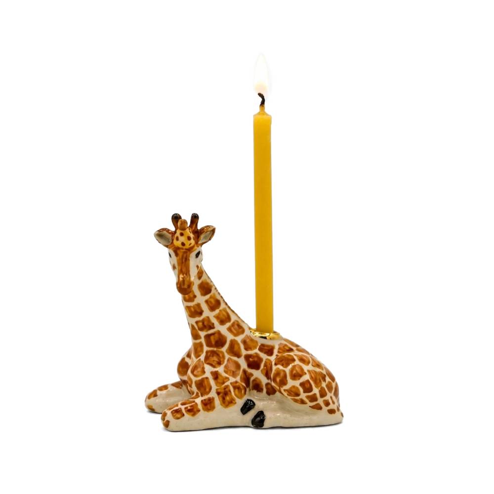 A ceramic giraffe-shaped candle holder with a lit yellow candle inserted into its neck, set against a plain white background.