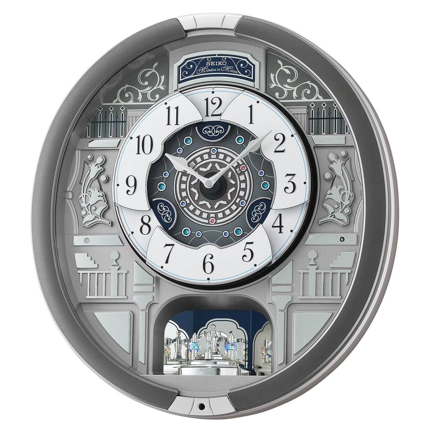 A highly detailed, circular wall clock with a complex architectural design in silver, white, and dark blue. The clock features intricate 3D elements, including a miniature castle on the lower arch, decorative pillars, and a central multi-layered dial with Roman numerals.