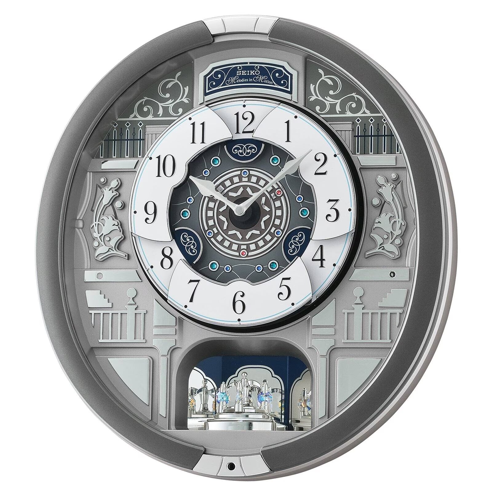 A highly detailed, circular wall clock with a complex architectural design in silver, white, and dark blue. The clock features intricate 3D elements, including a miniature castle on the lower arch, decorative pillars, and a central multi-layered dial with Roman numerals.