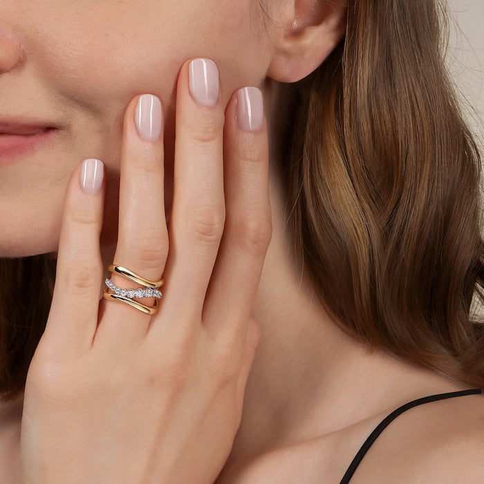 model wearing gold and silver ring with clear stones on a natural background