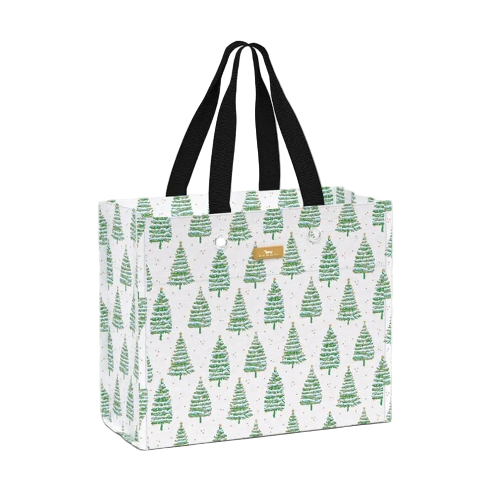 A white tote bag with a repeating green Christmas tree pattern, featuring black shoulder straps and a small tan leather brand patch that reads 'The Happy Bag'.