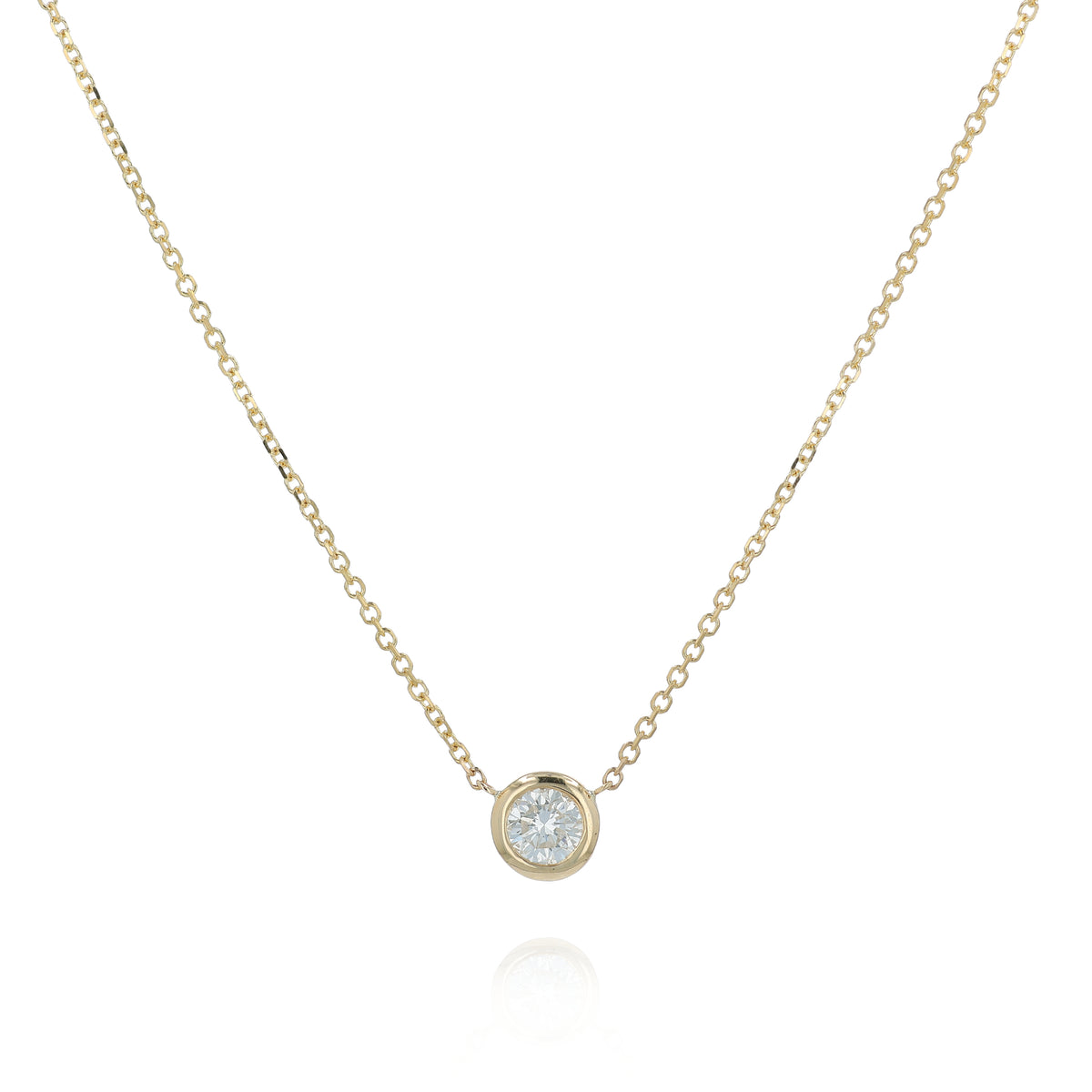 A delicate gold chain necklace with a small bezel-set pendant holding a clear round-cut diamond, displayed against a solid white background.