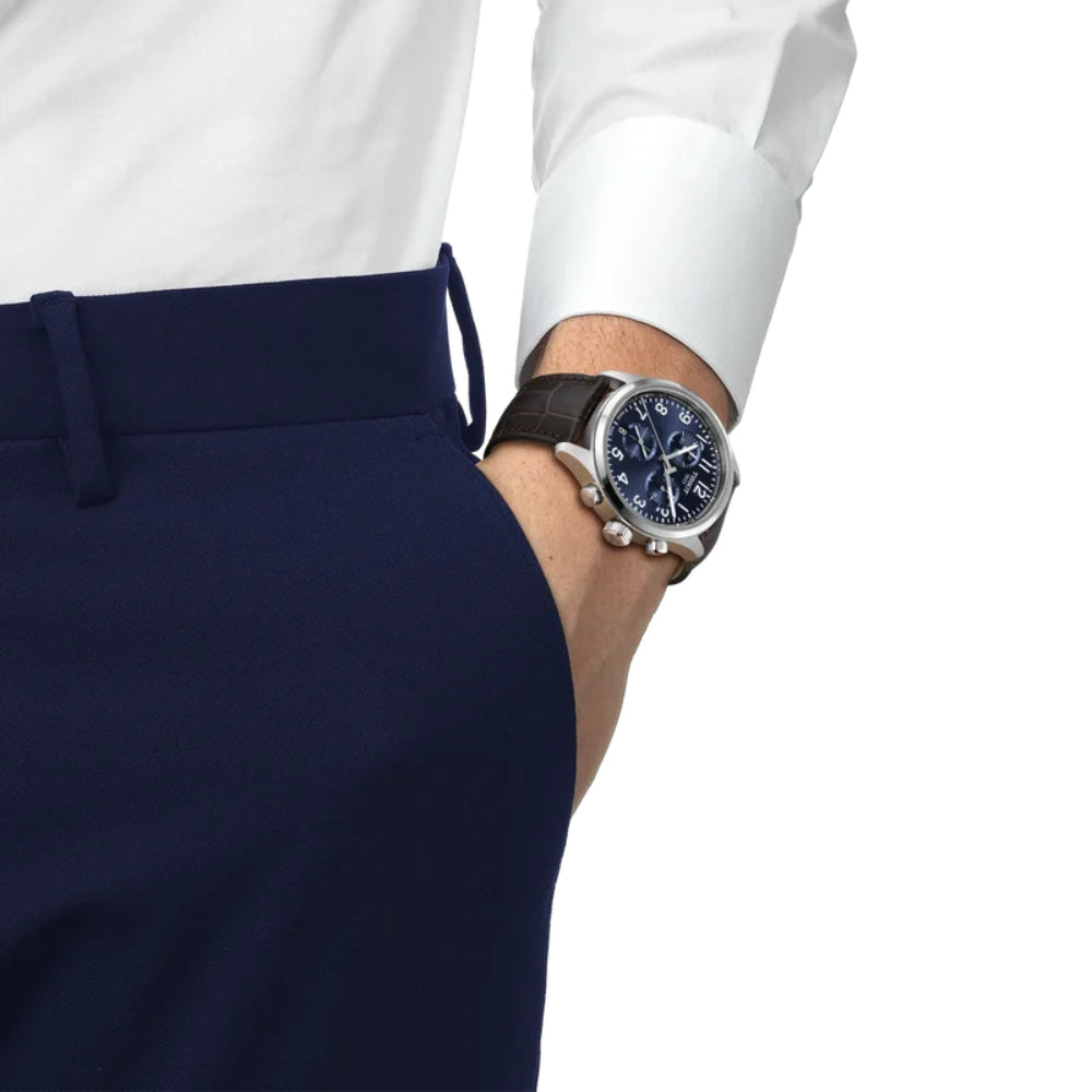 Close-up of a person wearing a watch with a white shirt and navy pants on a white background