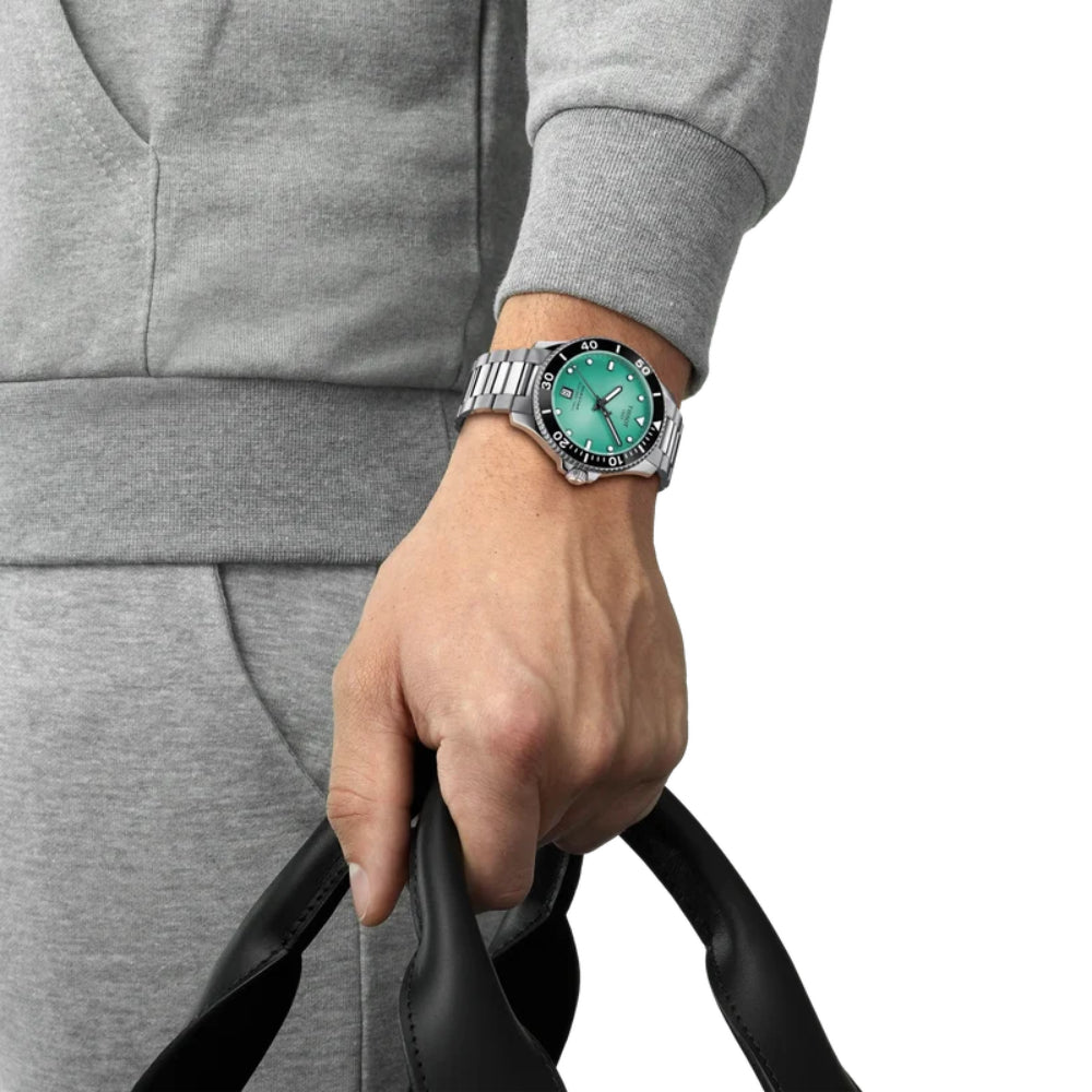 Person wearing a gray tracksuit with a turquoise wristwatch on a white background