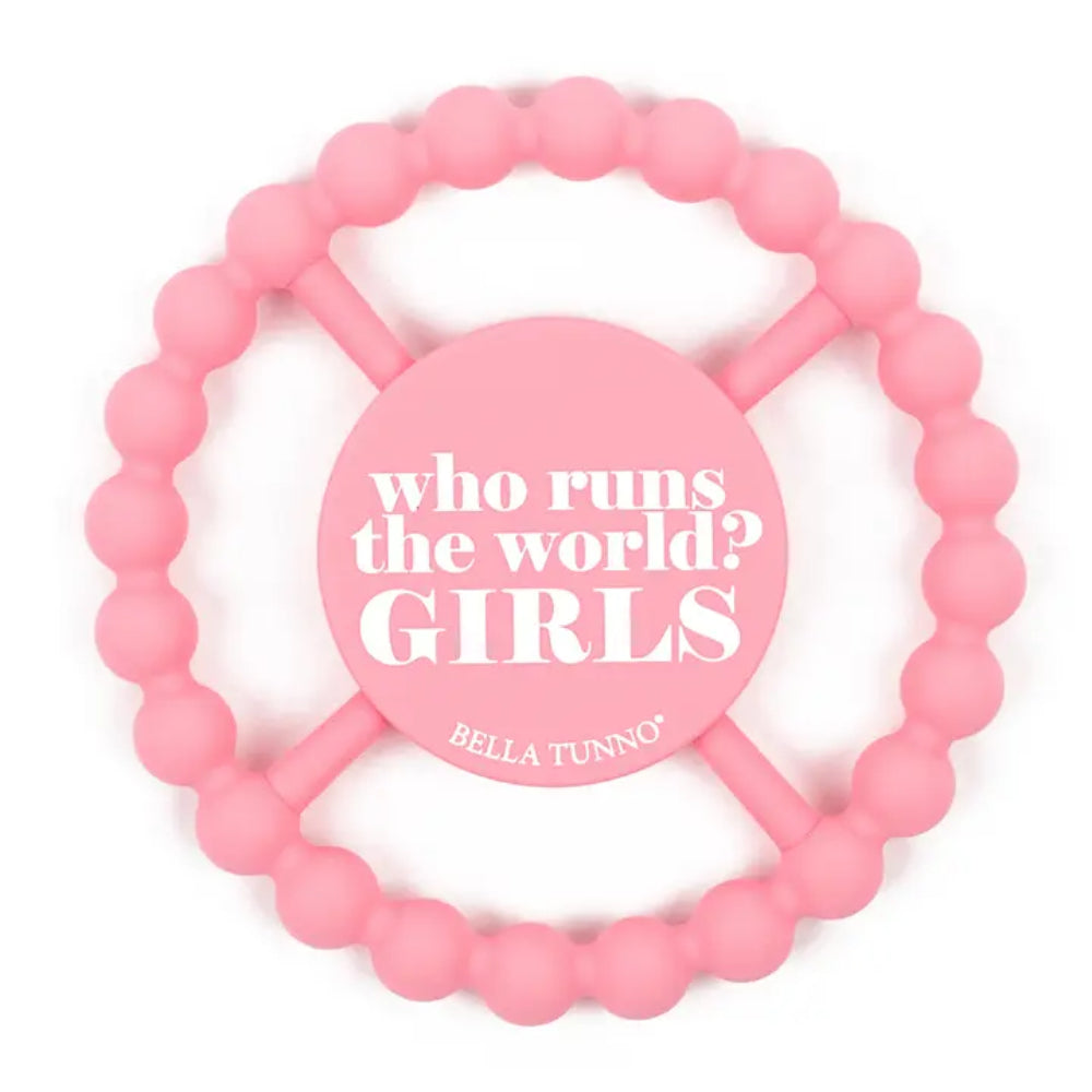 Pink silicone baby teether with a circular beaded ring and a central round pad that reads 'who runs the world? GIRLS' and 'BELLA TUNNO'.
