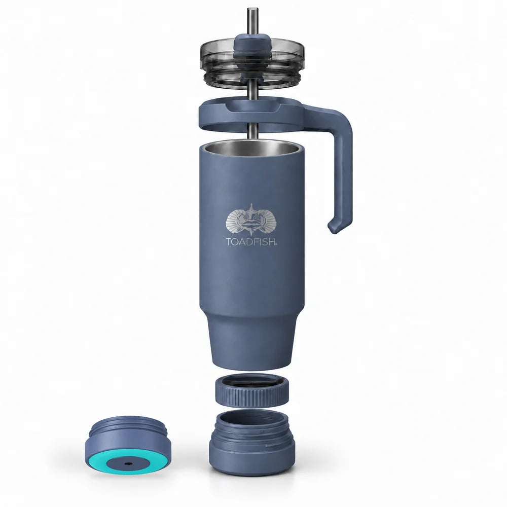 A disassembled TOADFISH insulated travel mug shown on a clean white background, with the main blue-gray body, handle, lid, and separate cap pieces arranged vertically. The mug has a silver-toned logo printed on the front.