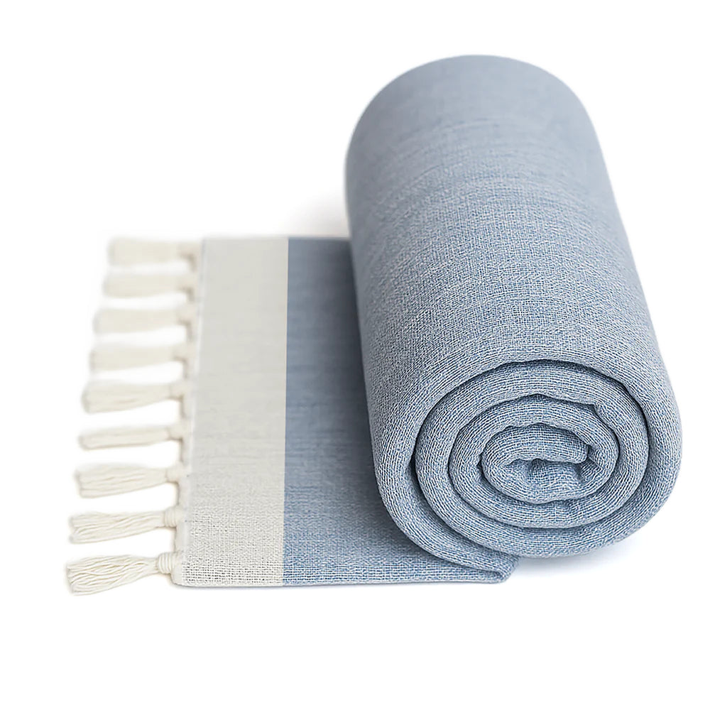 Blue rolled up towel with white fringe on a white background.