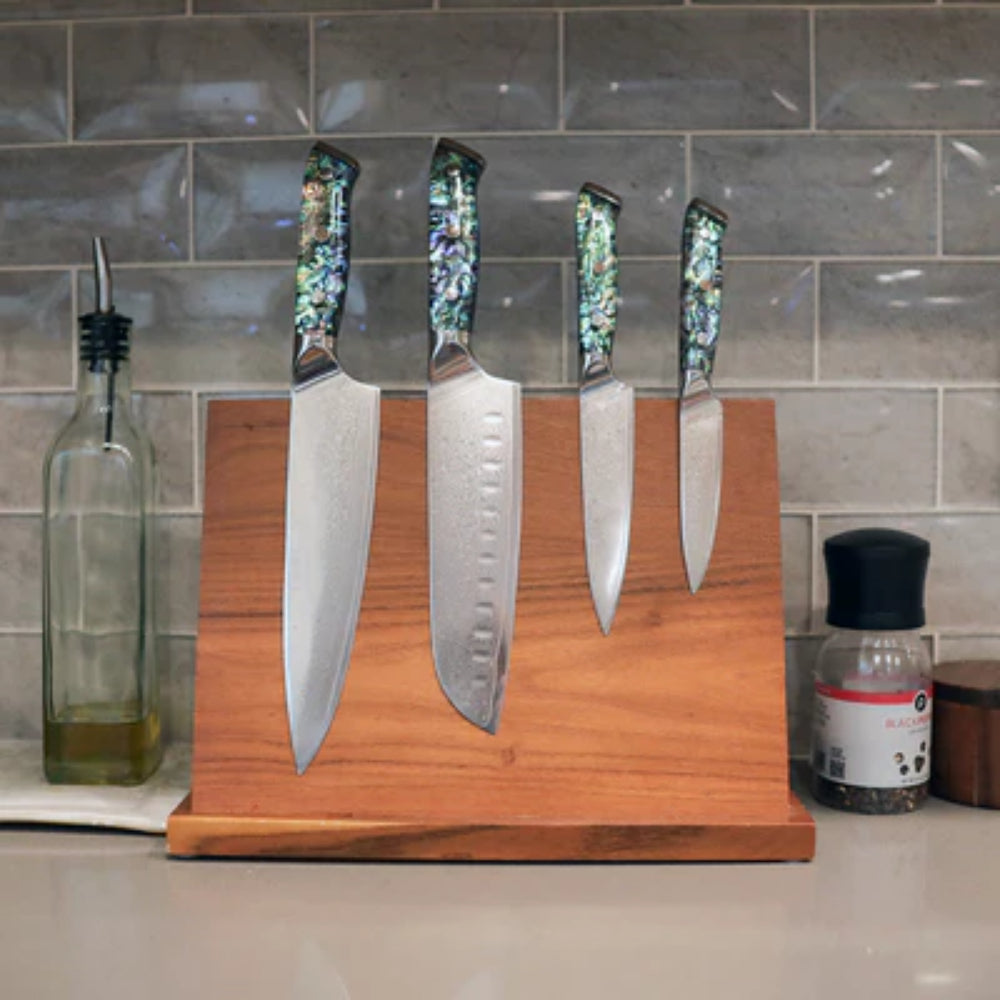 Set of knives with decorative handles on a wooden knife rack against a tiled wall.