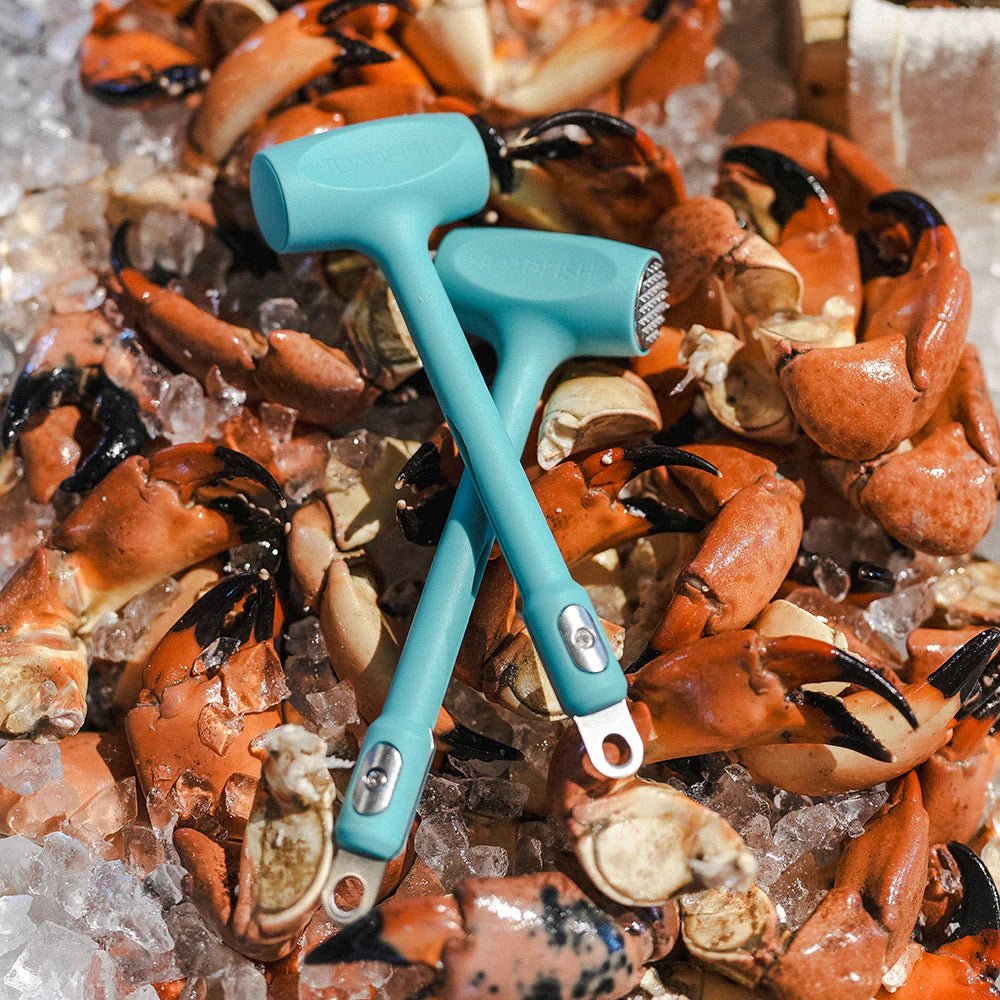 Two turquoise crab mallets on a bed of crab claws on ice.