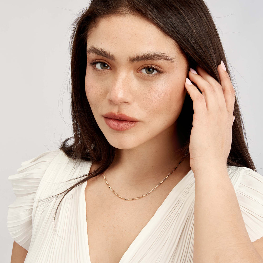 model wearing gold tone long link necklace on white background
