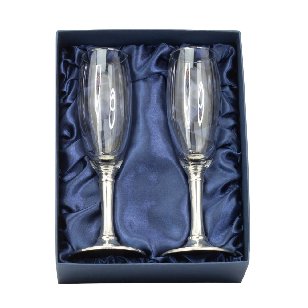 Two clear champagne flutes with silver bases in a blue box on a white background.