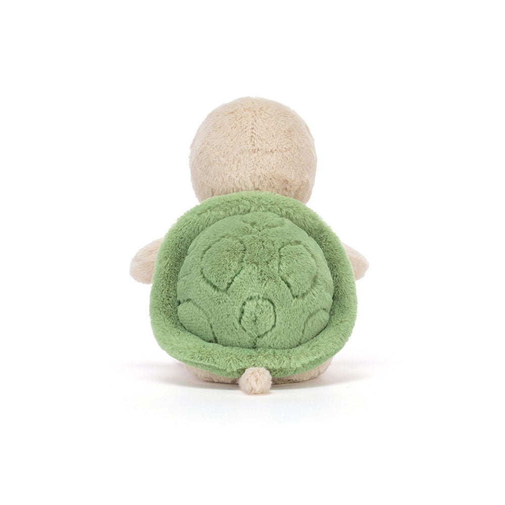 A photo of the back of a beige plush turtle toy with a smiling face and a green shell on a white background.