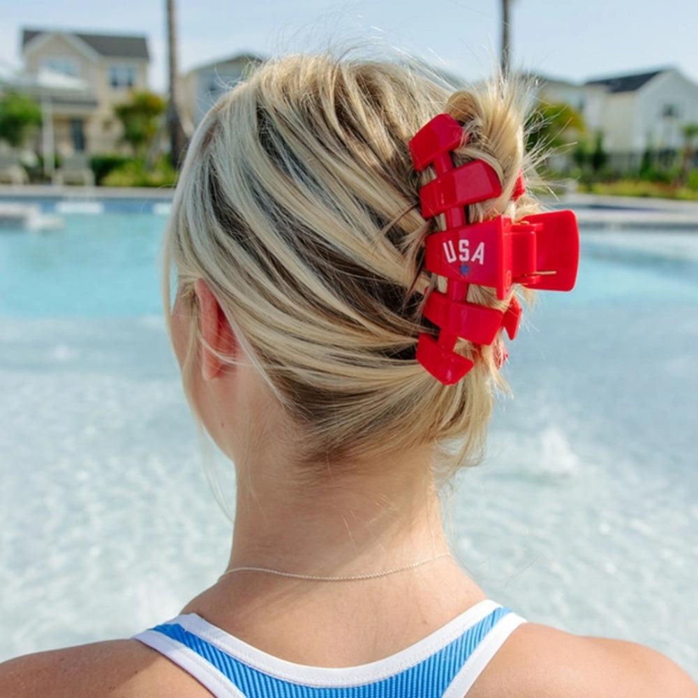 Person with red 'USA' hair clip in hair by a pool