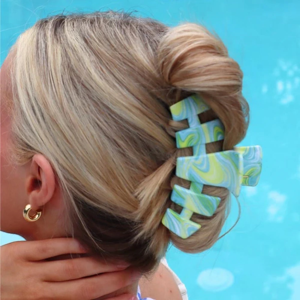 Woman with a bun holding a colorful hair clip against a blue background
