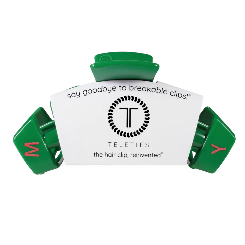 A green Teleties hair clip with a white paper insert card that reads 'say goodbye to breakable clips! TELETIES the hair clip, reinvented'.