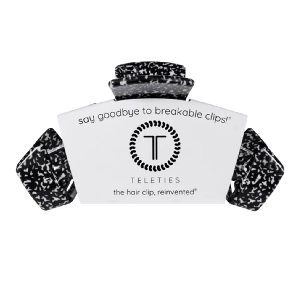 A Teleties hair clip shown open against a plain white background, with the brand card visible behind it. The clip has a black and white marbled or speckled pattern.