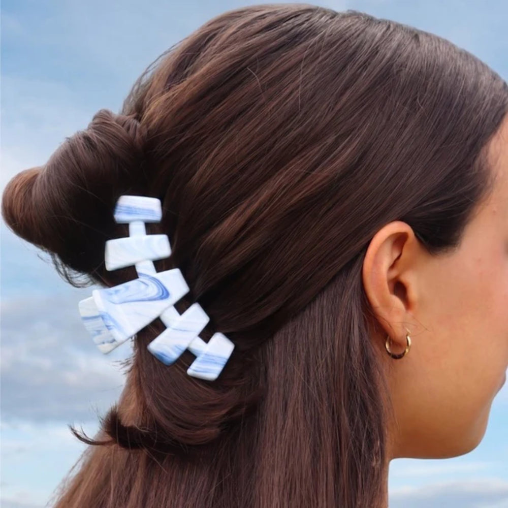 Person with a hair clip in their hair against a blue sky background