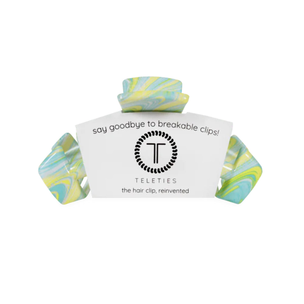 Marbled green and yellow hair clip with a white label on a white background