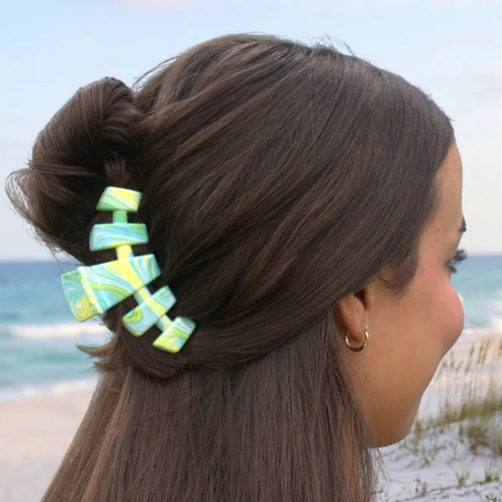 Woman with a colorful hair clip in her hair bun against a beach background