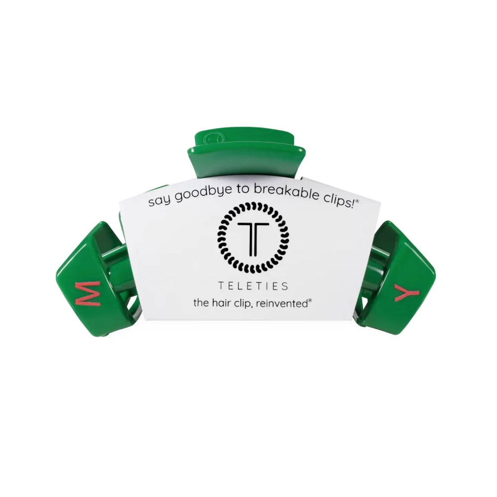 A green plastic hair clip with a white paper insert that reads 'say goodbye to breakable clips!' and shows the brand name 'TELETIES'.