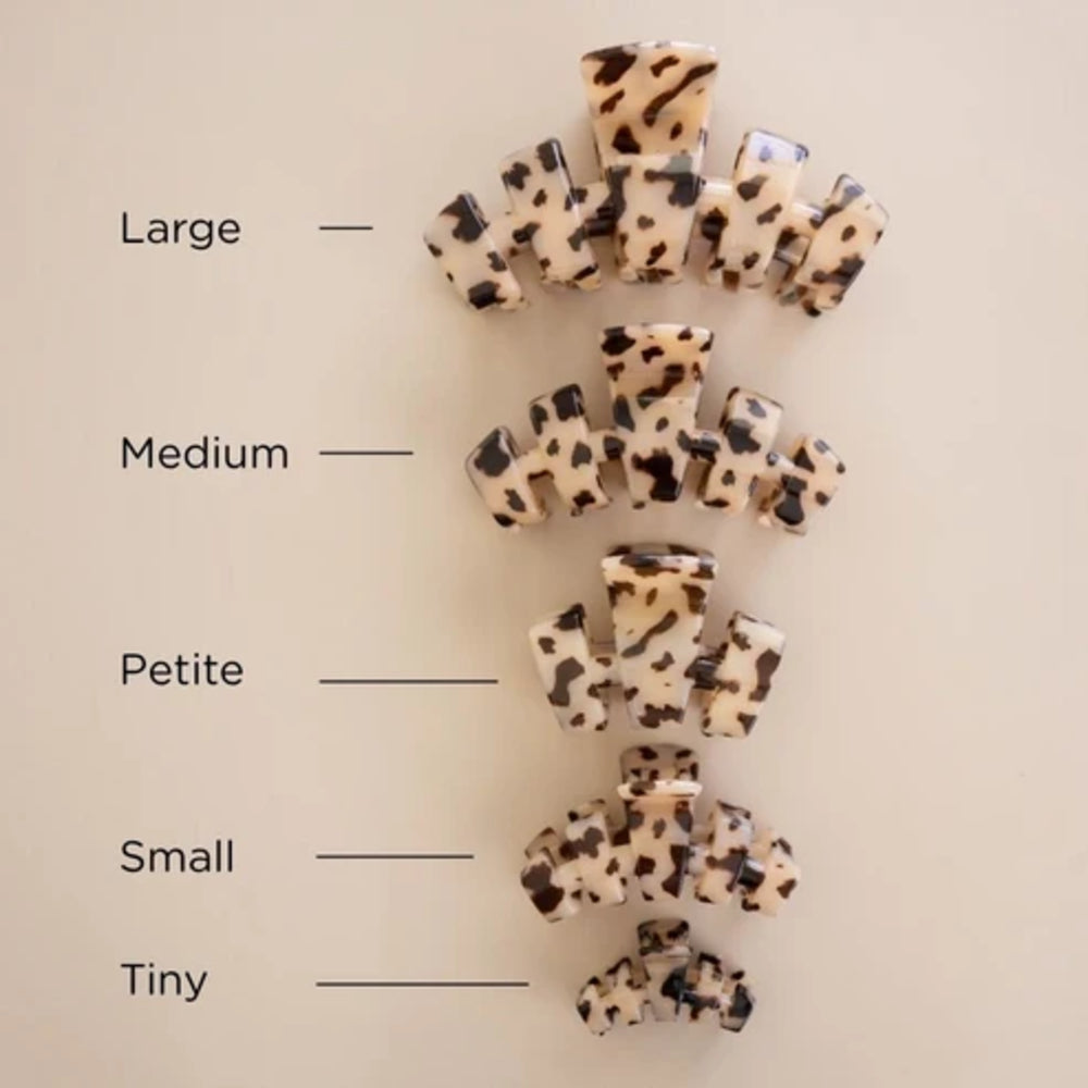 Five claw hair clips in different sizes are arranged vertically on a light beige background, with labels reading Large, Medium, Petite, Small, and Tiny beside each size.