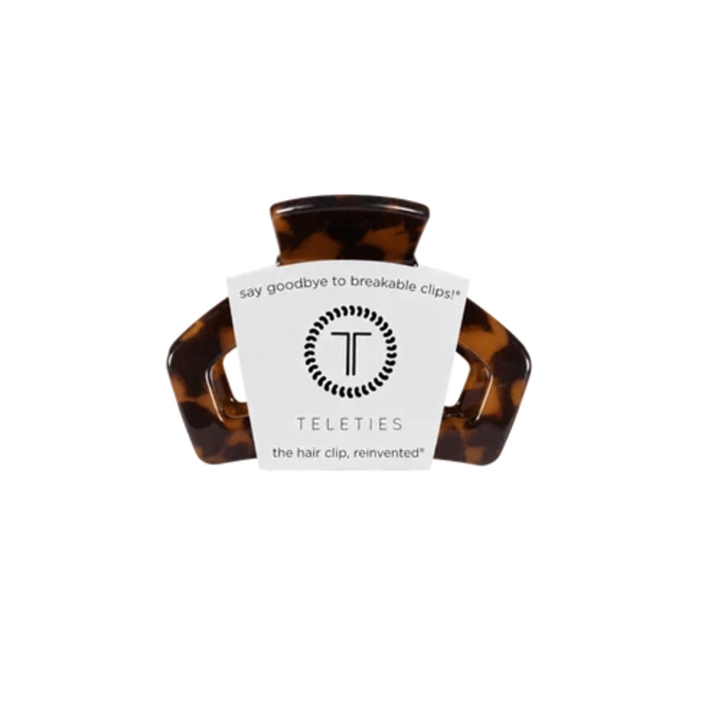 A Teleties hair clip in a dark tortoiseshell pattern, featuring a white paper label with the brand logo and name.
