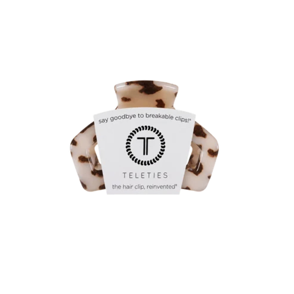 A Teleties hair clip in a brown and beige tortoiseshell pattern, featuring a white paper label wrapped around the front with the brand logo and name.
