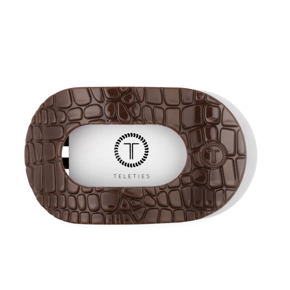 A Teleties personal flat round hair clip shown from the top, featuring a brown crocodile-embossed textured outer shell and a white inner body with the Teleties logo.