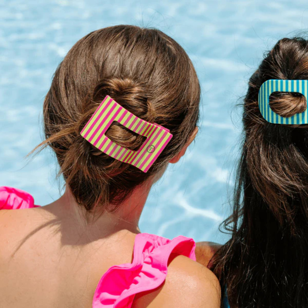 Two people with striped hair clips in their hair by a pool.