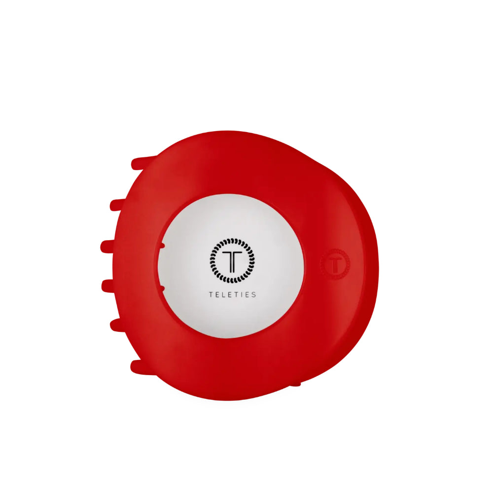 A red circular Teleties hair clip cover with a white center and black logo, shown on a plain white background.