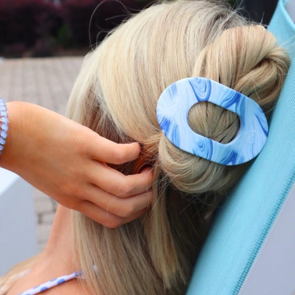 Person styling hair with a blue and white hair clip