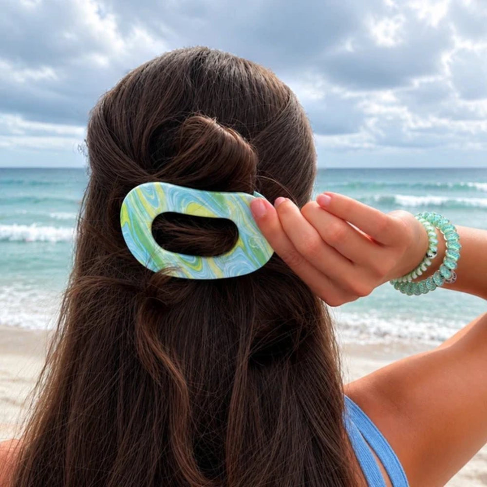 Person with a blue and green hair clip in their hair at the beach