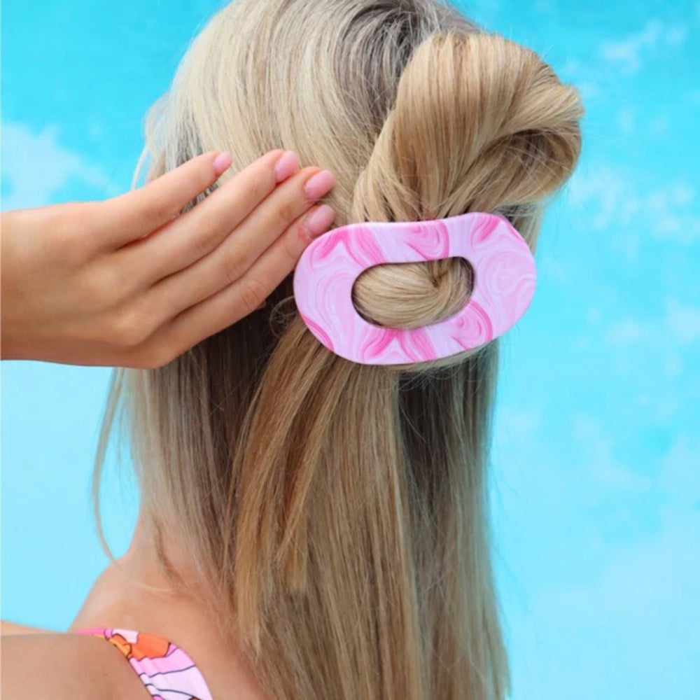 Person with pink and white patterned hair clip in their hair against a blue sky background