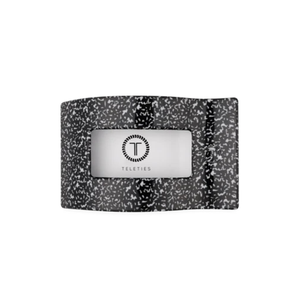 A black and white speckled fabric belt with a central silver metal plate featuring the 'Teleties' brand logo, set against a plain white background.